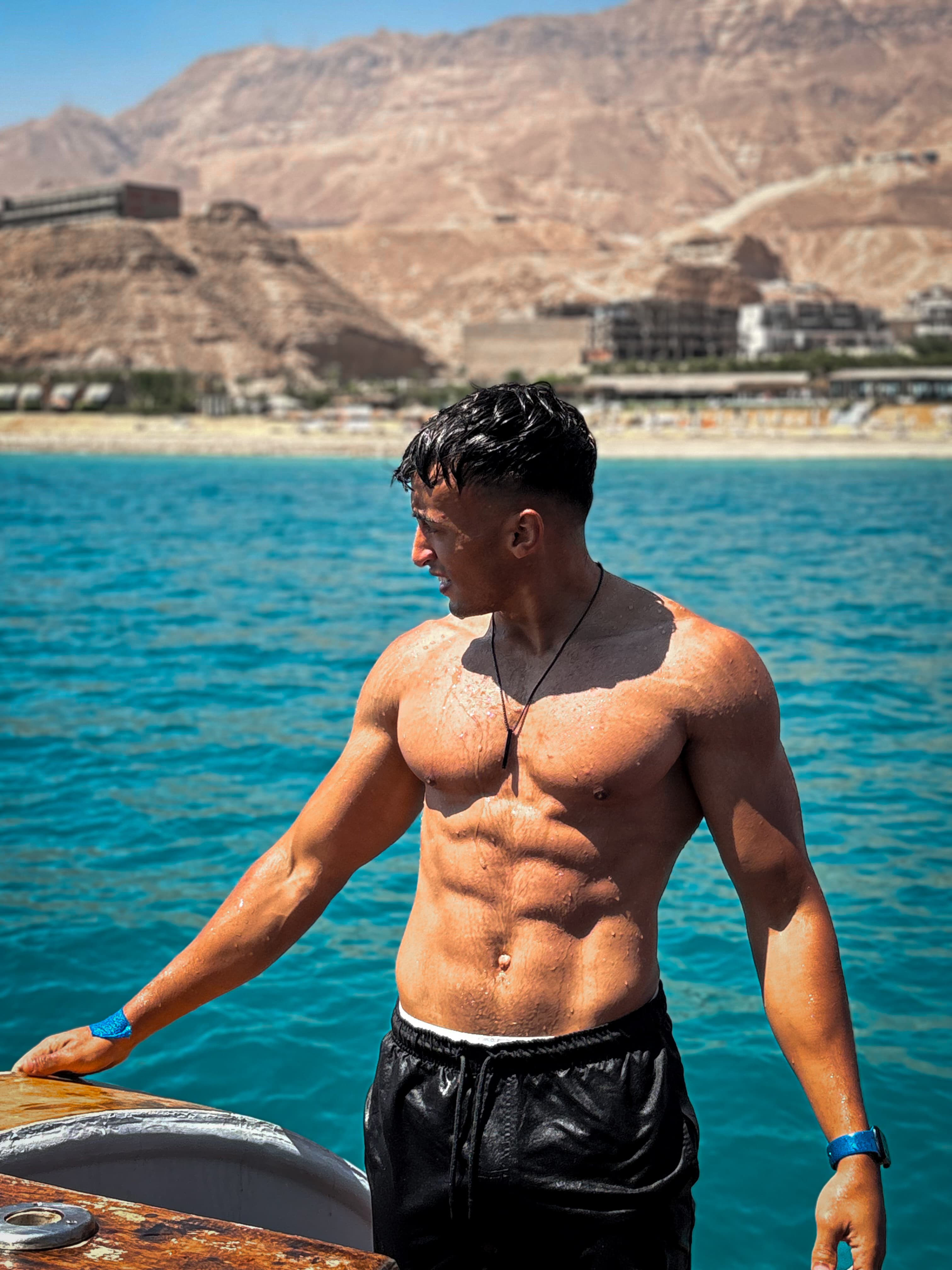 JOOOFIT coach showing a structured athletic physique by the sea